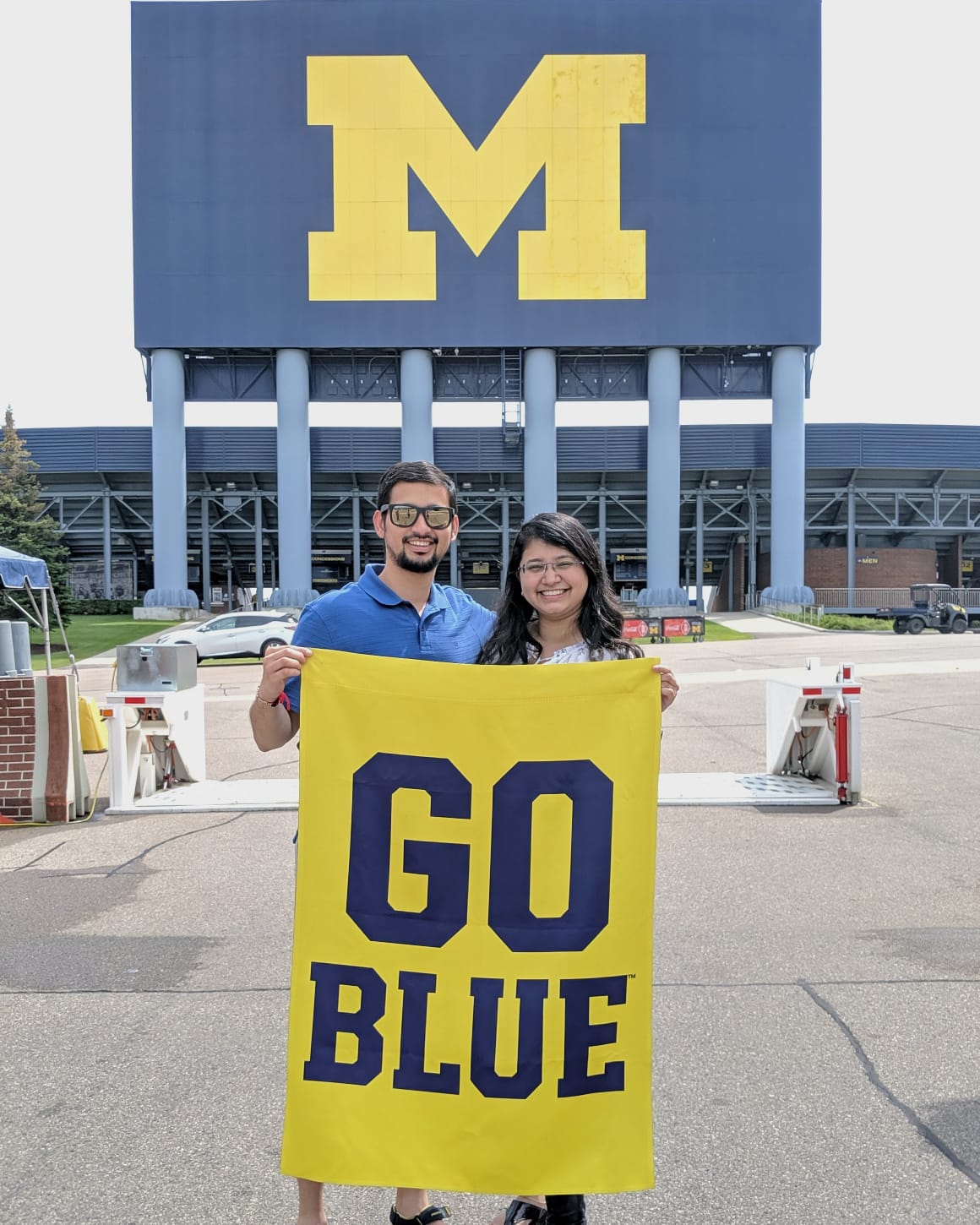 two people stand with block M flag outside Big House